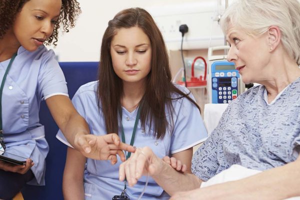 Two care workers talking to a patient