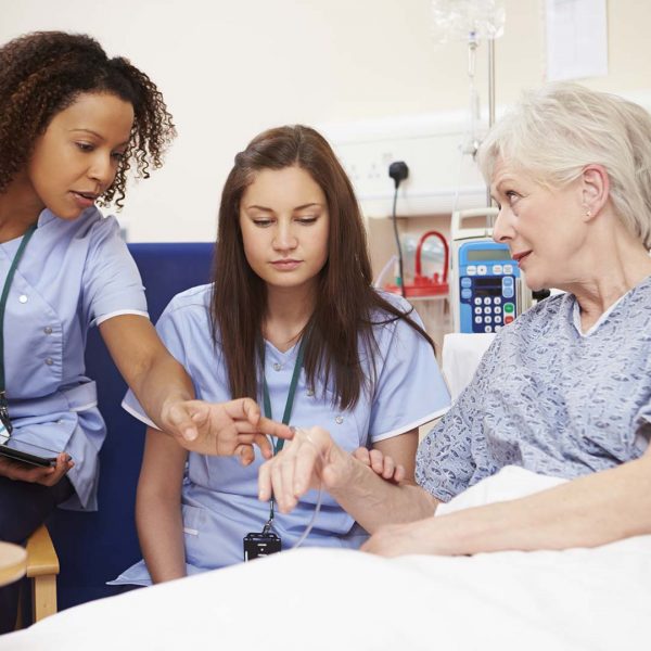 Two care workers talking to a patient